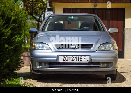 Silberblau 2002 Opel Vauxhall Astra geparkt vor der Hausgarage an sonnigen Tag außen Stockfoto