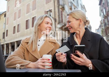 Zwei Frauen diskutieren, wie man sich über ein mobiles Netzwerk mit dem Internet verbindet Stockfoto