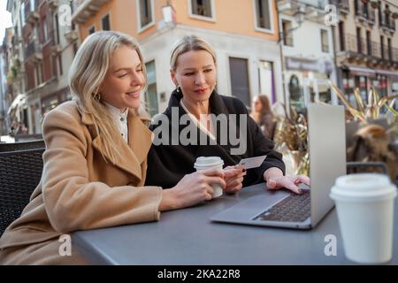 Zwei Frauen diskutieren, wie man sich über ein mobiles Netzwerk mit dem Internet verbindet Stockfoto