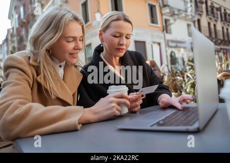 Zwei Frauen diskutieren, wie man sich über ein mobiles Netzwerk mit dem Internet verbindet Stockfoto