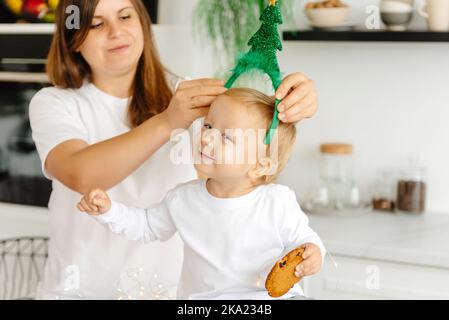 Ein fröhliches Kind in der Küche am Weihnachtstag mit einem Weihnachtsbaum. Fröhlicher Junge lachend Stockfoto