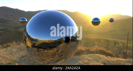 Große Stahlkugeln mit reflektierender Oberfläche fliegen im Morgengrauen über einem Bergdorf durch die Luft. Der Zweck ist unbekannt. Wahrscheinlich außerirdische Zivilisationen. Stockfoto