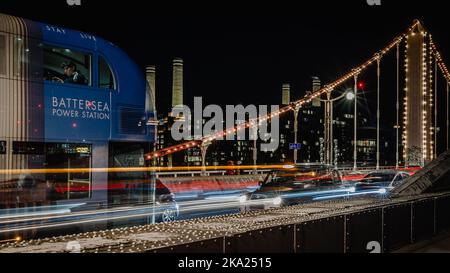 Ein Londoner Taxi im Verkehr auf der Chelsea Bridge mit einer Anzeige des Battersea Power Station in einem Bus und der Station im Hintergrund. Stockfoto