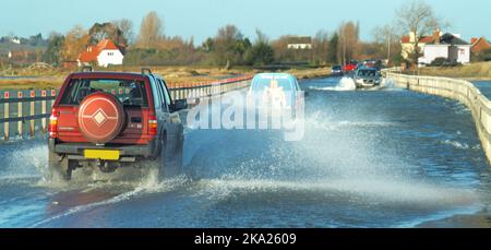 Fahrzeuge fahren bei Flut über den Fahrzeugdamm, der die einzige Straßenverbindung zum britischen Festland von Essex mit der Insel East und der Stadt West Mersea darstellt Stockfoto