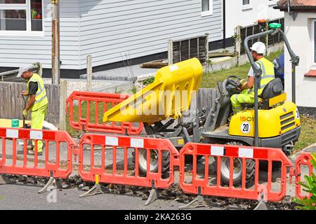 Arbeiter arbeiten mit Dumper LKW-Fahrer Infrastruktur Projekt Installation unterirdischer Breitband-Glasfaser-Kabel in Bürgersteig Graben England Großbritannien Stockfoto