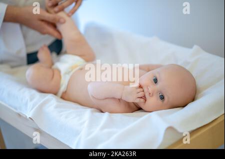 Chirurg überprüft die Gliedmaßen von Babys und bewegt sie Stockfoto