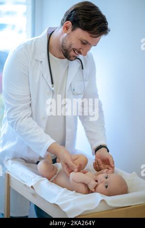 Chirurg überprüft die Gliedmaßen von Babys und bewegt sie Stockfoto