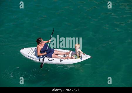 Eine Mutter und ein Kind sitzen auf einem Kajak in Newquay Bay in Cornwall in England im Vereinigten Königreich. Stockfoto