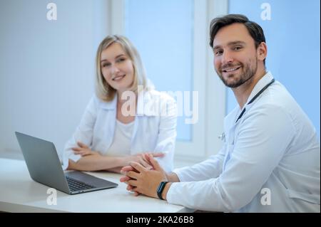 Zwei Ärzte sitzen dicht und diskutieren etwas Stockfoto