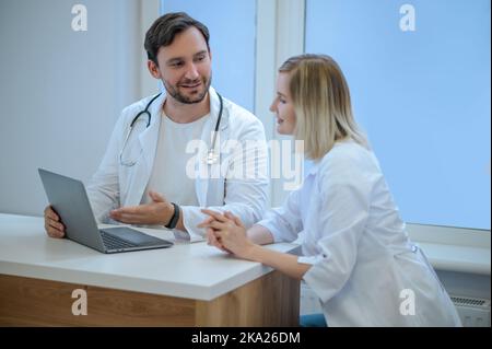 Zwei Ärzte sitzen dicht und diskutieren etwas Stockfoto
