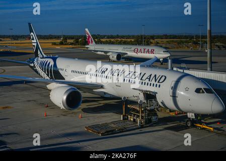 Eine stationäre Air New Zealand Boeing 787 Dreamliner und eine Katar Boeing 777 an einem Flughafenterminal. Stockfoto