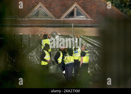 Sicherheitspersonal arbeitet daran, die Ansicht von Menschen zu verdecken, die als Migranten in der Manston-Kurzzeithalteeinrichtung für Immigration gedacht sind, die sich im ehemaligen Defense Fire Training and Development Center in Thanet, Kent, befindet. 700 Personen wurden aus Sicherheitsgründen in die Manston-Einrichtung gebracht, nachdem am Sonntag Brandanzündvorrichtungen auf ein Migrantenzentrum der Grenztruppen in Dover geworfen wurden. Bilddatum: Montag, 31. Oktober 2022. Stockfoto
