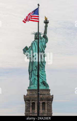 Rückansicht der Freiheitsstatue mit Sternen und Streifen Flagge winken Stockfoto