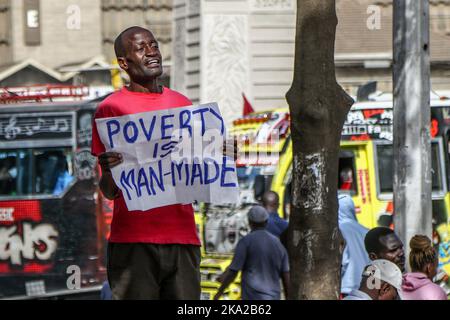 Nairobi, Kenia. 25. Oktober 2022. Julius Kamau, ein lautstarker kenianischer Menschenrechtsaktivist, spricht während er ein Plakat mit der Aufschrift ‘Armut ist menschengemacht' auf den Straßen des Nairobi Central Business District hält. Julius wurde während seiner Proteste gegen Armut und Ungerechtigkeit in Kenia mehrmals von der Polizei verhaftet und schikaniert. Trotz der Verfassung, die das Recht garantiert, zu protestieren und Petitionen an öffentliche Behörden zu stellen, hat die Polizei in zahlreichen Fällen Proteste mit brutaler Gewalt gebrochen und Protestierenden gesetzwidrig verhaftet. Kredit: SOPA Images Limited/Alamy Live Nachrichten Stockfoto