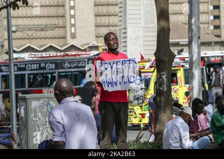 Nairobi, Kenia. 25. Oktober 2022. Julius Kamau, ein lautstarker kenianischer Menschenrechtsaktivist, spricht während er ein Plakat mit der Aufschrift ‘Armut ist menschengemacht' auf den Straßen des Nairobi Central Business District hält. Julius wurde während seiner Proteste gegen Armut und Ungerechtigkeit in Kenia mehrmals von der Polizei verhaftet und schikaniert. Trotz der Verfassung, die das Recht garantiert, zu protestieren und Petitionen an öffentliche Behörden zu stellen, hat die Polizei in zahlreichen Fällen Proteste mit brutaler Gewalt gebrochen und Protestierenden gesetzwidrig verhaftet. Kredit: SOPA Images Limited/Alamy Live Nachrichten Stockfoto