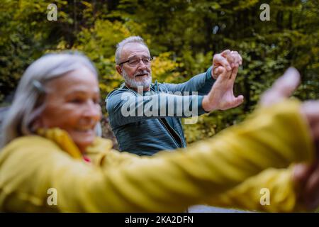 Glückliches Seniorenpaar beim Stretching beim Wandern im Herbstwald. Stockfoto