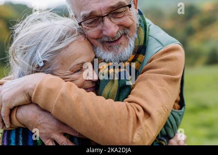 Das verliebte Senioren-Paar umarmt sich in der herbstlichen Natur. Stockfoto