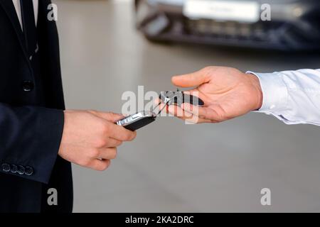 Der Autoverkäufer gibt die Schlüssel den Kunden, die den Kaufvertrag unterzeichnet haben Stockfoto