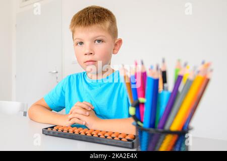 Kind mit Lernschwierigkeiten in der Ergotherapie. Ein Junge, der während der Mathe-Nachhilfe spielerische Übungen macht. Stockfoto