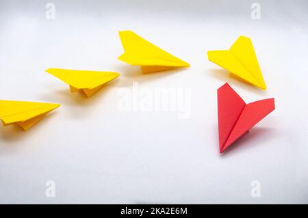 Rotes Papier Flugzeug Origami führenden gelben Ebenen auf weißem Hintergrund. Konzept der Führungsqualitäten. Stockfoto