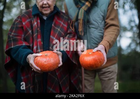 Seniorenpaar mit Kürbissen im Herbstwald. Stockfoto