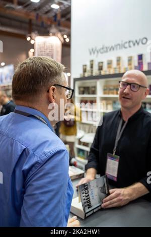 Kraków, Polen - 28.-30. Oktober 2022: Robert Małecki, polnischer Schriftsteller, signiert Bücher während der Krakauer Buchmesse 2022 auf der Internationalen Ausstellung und in Conven Stockfoto