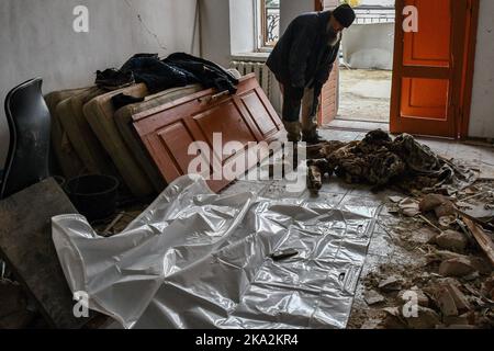 Ein Mönch sieht sich die Überreste eines Mannes an, der von Rettern aus den Trümmern der Heiligen Berge Lavra der Heiligen Dormition in der befreiten Stadt Sviatohirsk entfernt wurde. Russland hat eine Welle von Marschflugkörpern auf Wasserkraftwerke und andere kritische Infrastrukturen in der Ukraine gestartet, wobei Explosionen in der Nähe der Hauptstadt Kiew und in mindestens 10 anderen Städten und Regionen gemeldet wurden. Das Luftkommando der Ukraine sagte, dass es 44 von 50 feindlichen Raketen abgeschossen habe. (Foto von Andriy Andriyenko / SOPA Images/Sipa USA) Stockfoto