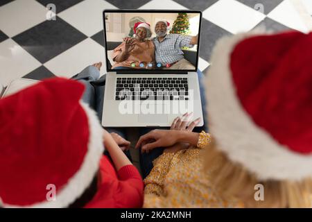 Ein vielseitiges Paar, das ein weihnachtsvideo mit einem afroamerikanischen Seniorenpaar führt Stockfoto