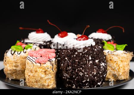 Kuchen mit Schokolade, Kirschen und Rahm auf schwarzem Hintergrund. Stockfoto