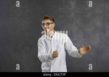 Lustige glücklich jungen Kerl in modernen Strolchen Leben Pixel Sonnenbrille tanzen und genießen Musik Stockfoto