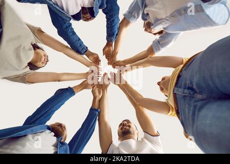 Ein glückliches Team junger Menschen hebt die Hände und verbindet sie mit Einheit und Solidarität. Stockfoto