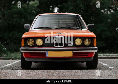 Eine Nahaufnahme eines klassischen orangefarbenen BMW 320 Autos im Retro-Stil auf einem Parkplatz Stockfoto