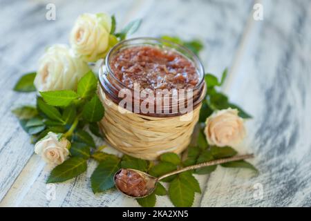 Rosafarbene Marmelade mit Rosenblüten-rosafarbene Blütenblattkonfitüre in einem Glasglas auf neutralgrauem Küchentisch mit Kopierfläche Stockfoto