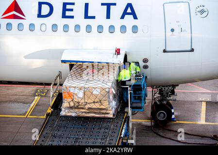 Nahaufnahme von Personen, die am Flughafen Schiphol Amsterdam Fracht in das Delta-Flugzeug laden Stockfoto