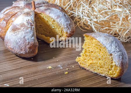 Kürbisbrot in Form eines Kürbisses auf einem Holztisch. Stockfoto