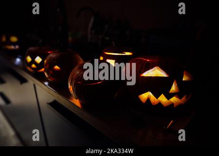 Geringe Schärfentiefe (selektiver Fokus) mit verschiedenen geschnitzten Halloween Kürbissen (Jack-o-Laternen) im Dunkeln mit elektrischen Kerzen im Inneren. Stockfoto