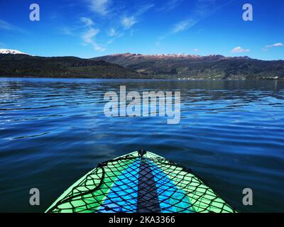 Eine schöne Aufnahme eines Bootes, das im Meer vor grünen Bergen segelt Stockfoto