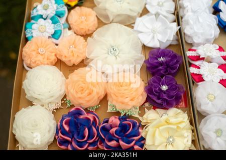 Schleifen aus Stoff. Handgefertigte Haarspangen. Blumen aus Stoffklappen. Haarschmuck. Details von FAIR. Stockfoto