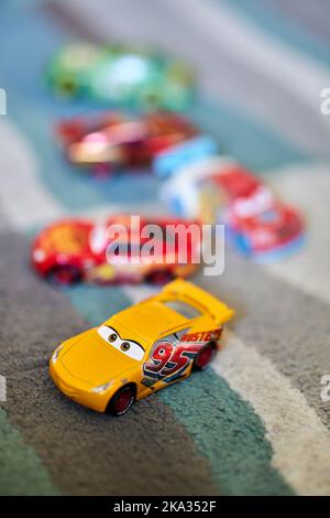 Eine vertikale, selektive Fokusaufnahme des Spielzeugautos Mattel Cruz Ramirez aus dem Disney Pixar Cars Film auf einem Teppich Stockfoto