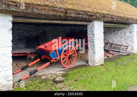 Rot und blau bemalter Pferdewagen in einem Bauernhof byre. Stockfoto