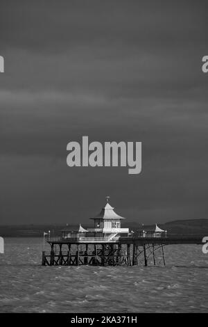 Eine Graustufenaufnahme des Clevedon Pier im Meer unter bewölktem Himmel in Somerset, Großbritannien Stockfoto