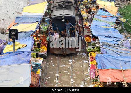 Dhaka, Dhaka, Bangladesch. 31. Oktober 2022. Ein Pendlerzug fährt durch den Jurain Railgate Markt in Dhaka. Verkäufer verkaufen Obst und Gemüse nur wenige Zentimeter von der Bahnlinie entfernt. Zwei Züge fahren pro Stunde mit einer Geschwindigkeit von etwa 30 Kilometern durch diesen Markt. (Bild: © Syed Mahabubul Kader/ZUMA Press Wire) Stockfoto