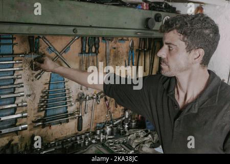 Professioneller Mechaniker, der Reparaturwerkzeuge in der Werkstatt wählt Stockfoto