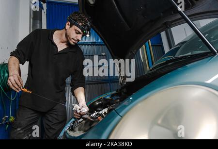 Mechaniker überprüft Motorölmessstab Stockfoto