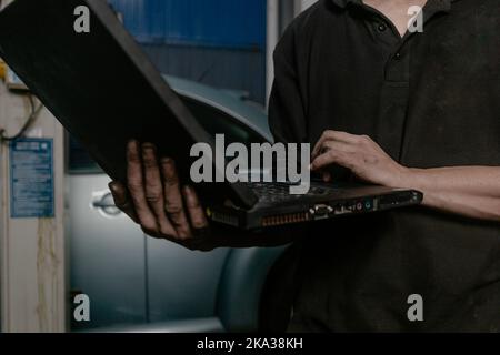 Automechaniker, der in der Werkstatt am Laptop arbeitet Stockfoto