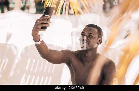 Ein froher schwarzer Tourist, der Selfie am Strand gemacht hat Stockfoto