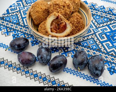 Tonschüssel mit Pflaumenfüllung, mit Zucker bedeckt und geröstete Paniermehl Kruste und Pflaumen in der Nähe Stockfoto