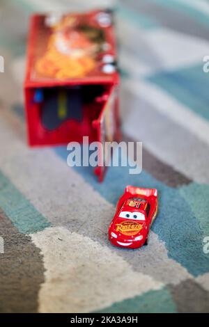 Eine vertikale, selektive Fokusaufnahme des Spielzeugautos Mattel Lightning McQueen aus dem Disney Pixar Cars Film auf einem Teppich Stockfoto