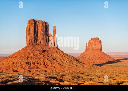 Zwei Fäustlinge, butte mesa, Nahaufnahme mit farbenprächtiger rot-oranger Felsfarbe am Horizont in den Monument Valley Canyons bei sonnigem Sonnenuntergang in Arizona Stockfoto