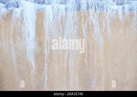 Alte Betonwand stuckblau und beige sandig mit salzenden Tropfen Flecken wie Wasserfall. Stockfoto